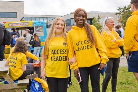 2 smiling Access Leaders in yellow at the Access and Lifelong Learning Welcome